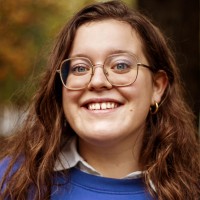 photo de jeanne le mercier, éditrice Bd chez nathan. Jeune femme souriante aux cheveux bruns, qui porte des lunettes